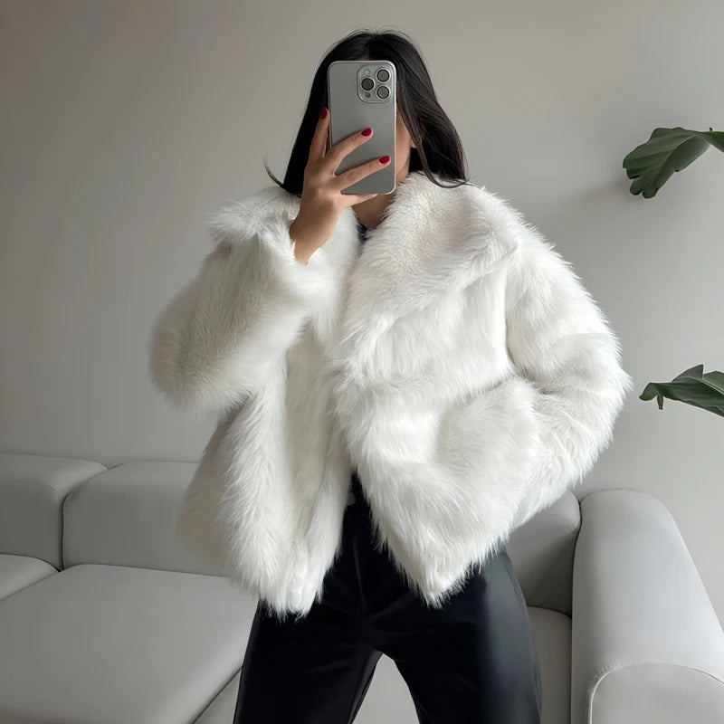 Woman wearing a white faux fur jacket and black pants in a modern living room