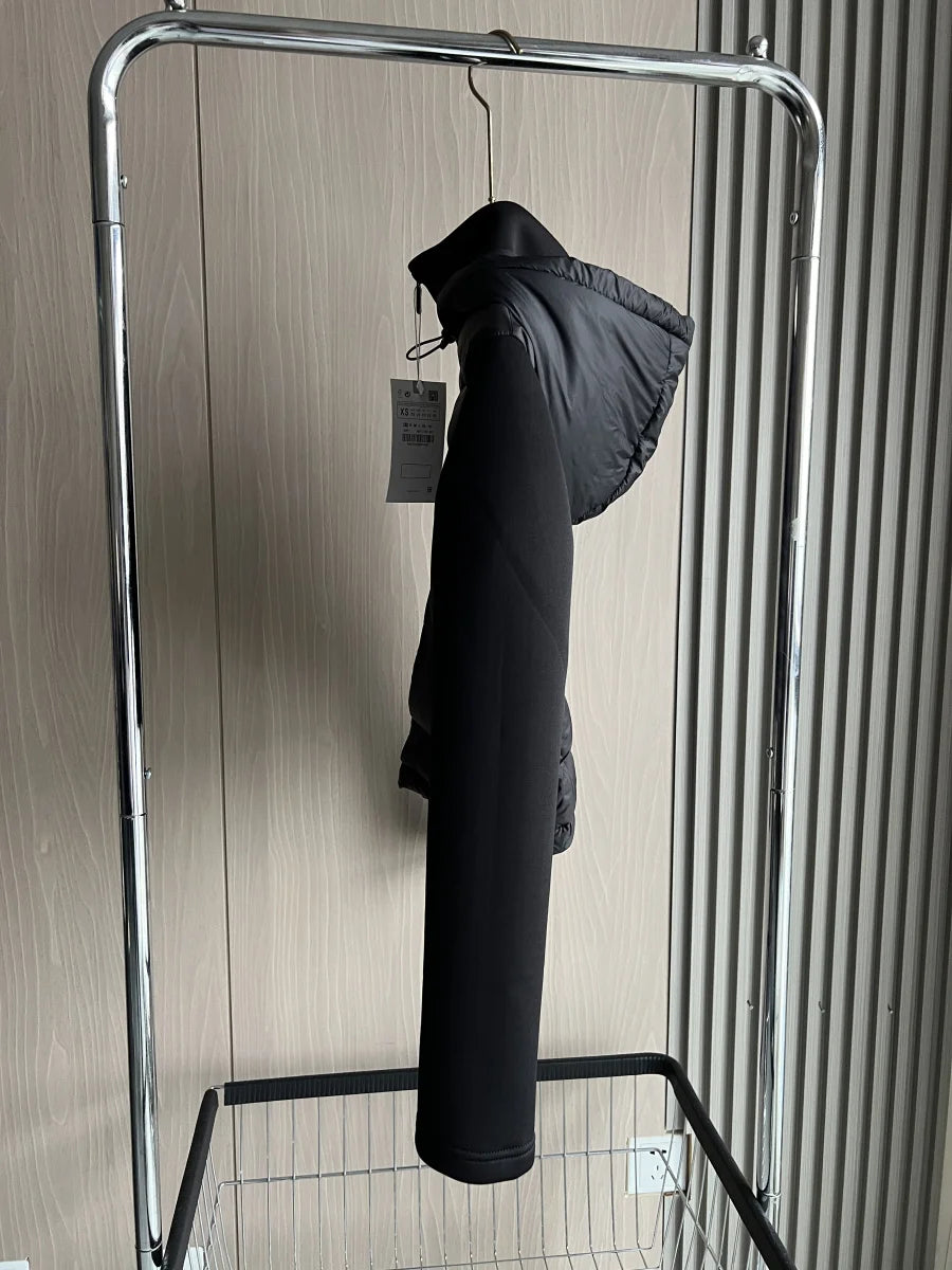 Modern black puffer jacket with hood and tag, hanging on metal rack in minimal setting