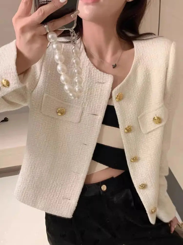 Woman wearing elegant white tweed jacket with gold buttons and striped crop top