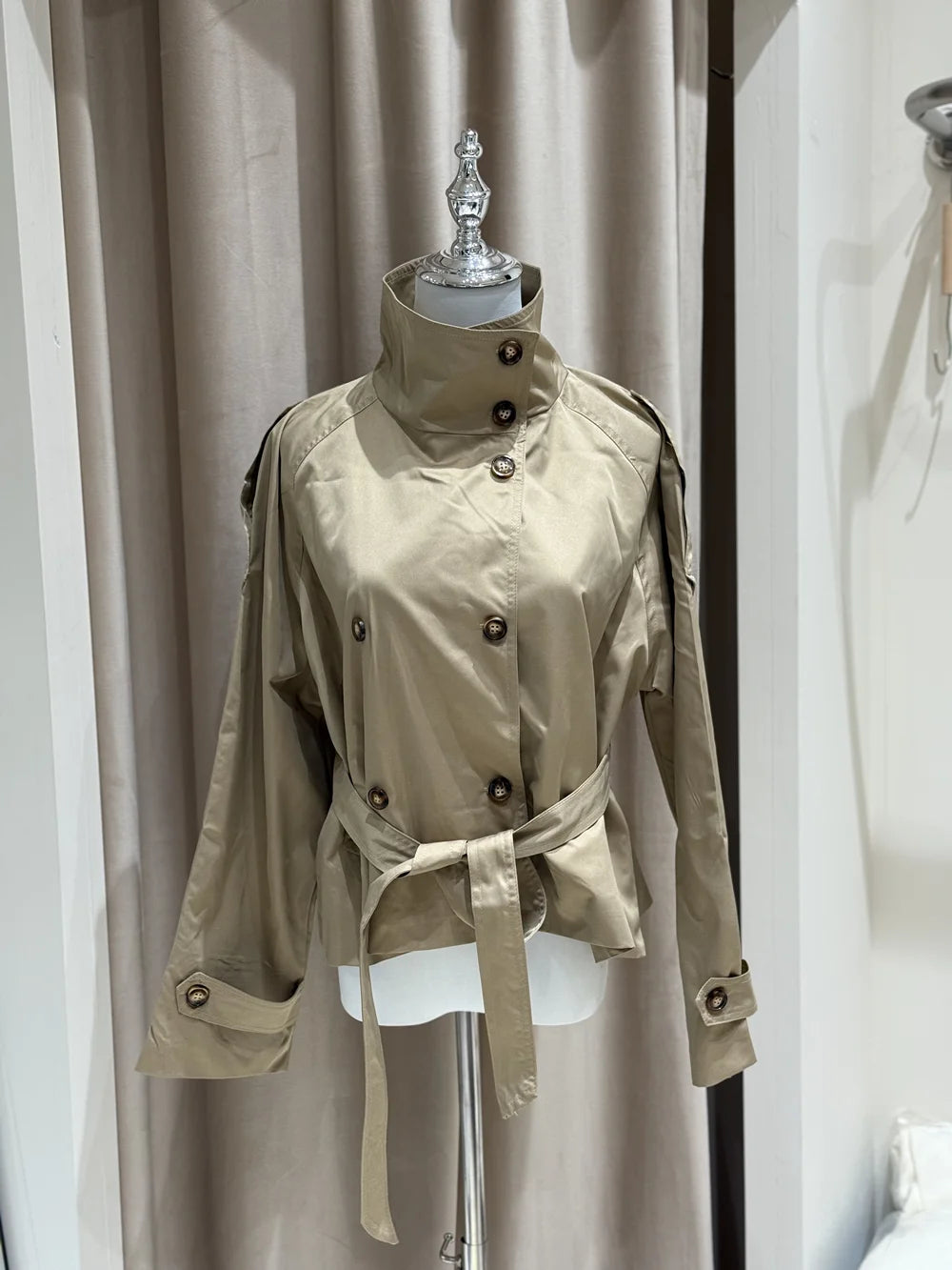 Beige belted trench jacket with high collar and button details on mannequin