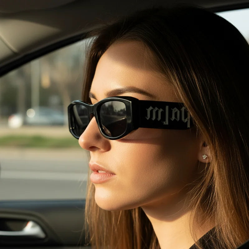 Woman wearing bold black square sunglasses with thick frames in a car, modern fashion accessory