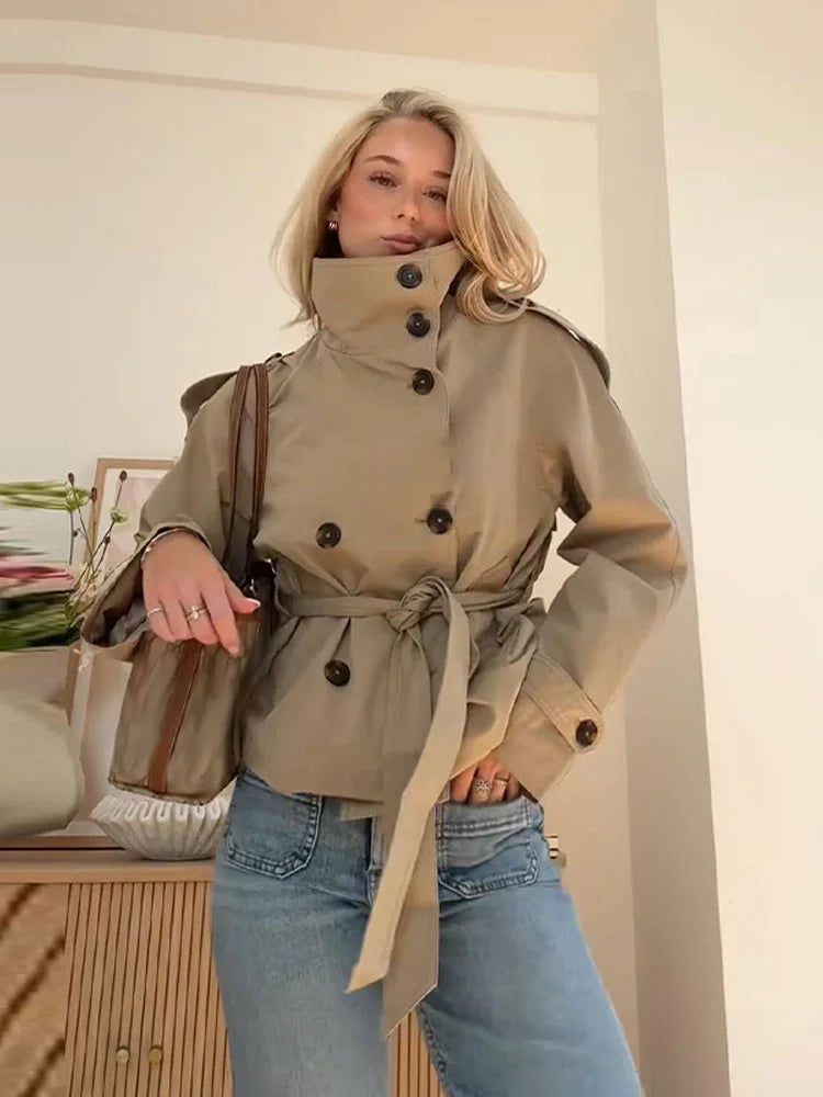 Blonde woman in a beige belted trench coat and blue jeans, modern chic fashion look