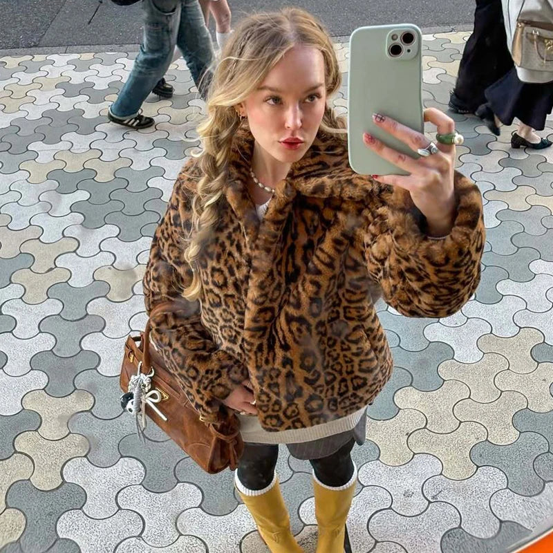Woman wearing faux fur leopard print coat, yellow boots, and brown bag taking mirror selfie outdoors